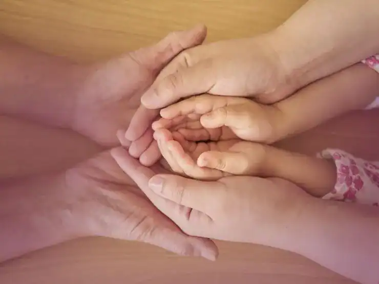 ¿Qué es la Ley de la Pertenencia? Imagen simbólica de tres generaciones: la mano de una niña dentro de la de su madre y la de su abuela envolviéndolas.