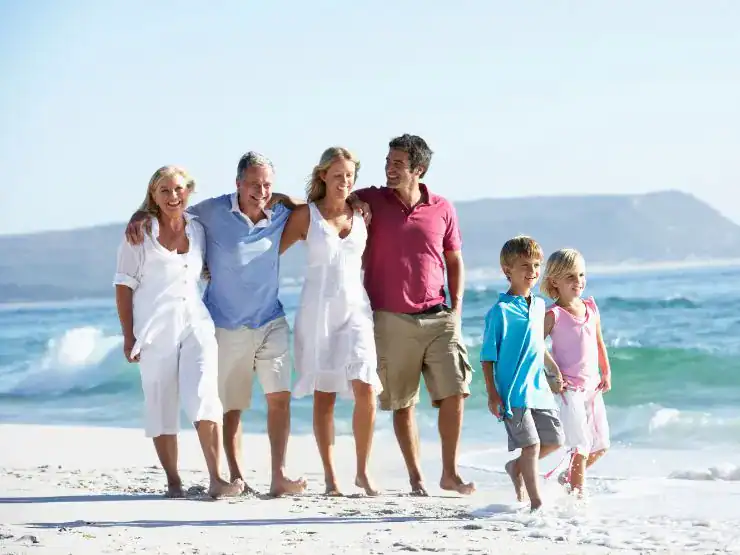 Una familia abrazándose y caminando por la playa, con los hijos pequeños al frente, ilustrando lo que son los Enredos Afectivos Familiares.